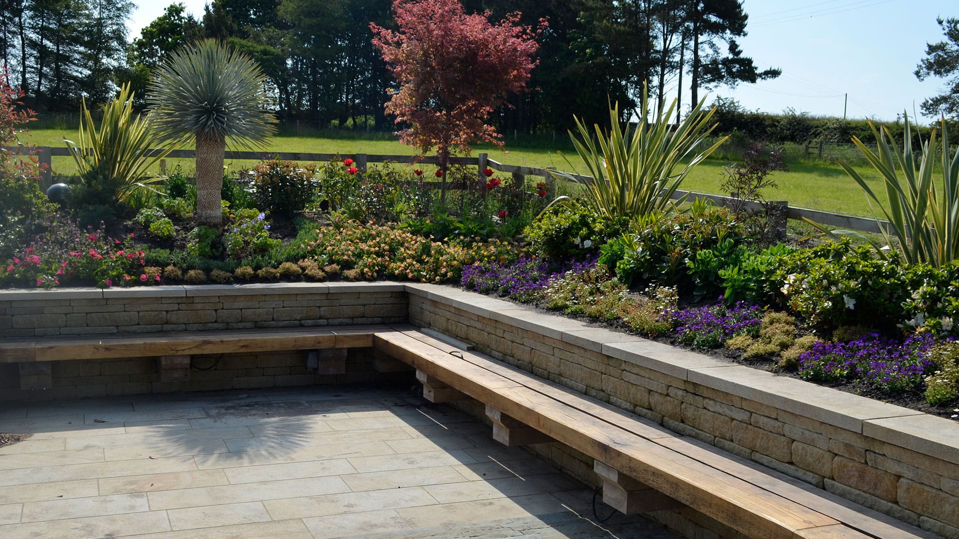 Close-up of a boundary wall with integrated stone seating, showcasing a seamless design that combines practical seating with the strength of the wall