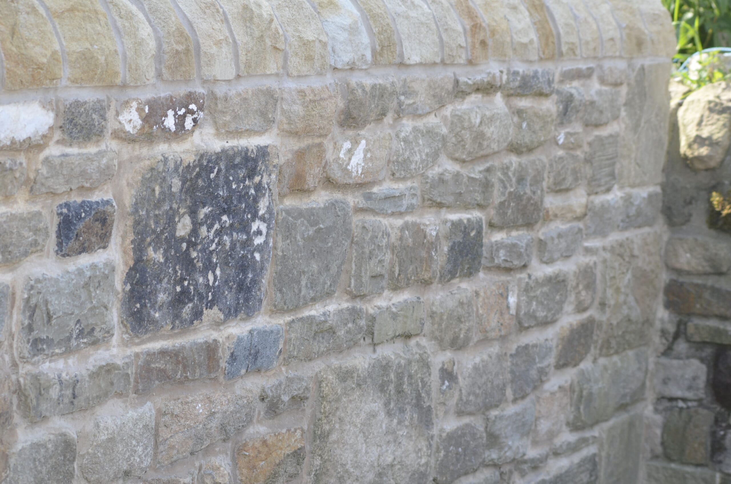 Close-up of a neatly constructed mortared stone wall, showcasing interlocked stones bound with mortar for strength and a polished appearance