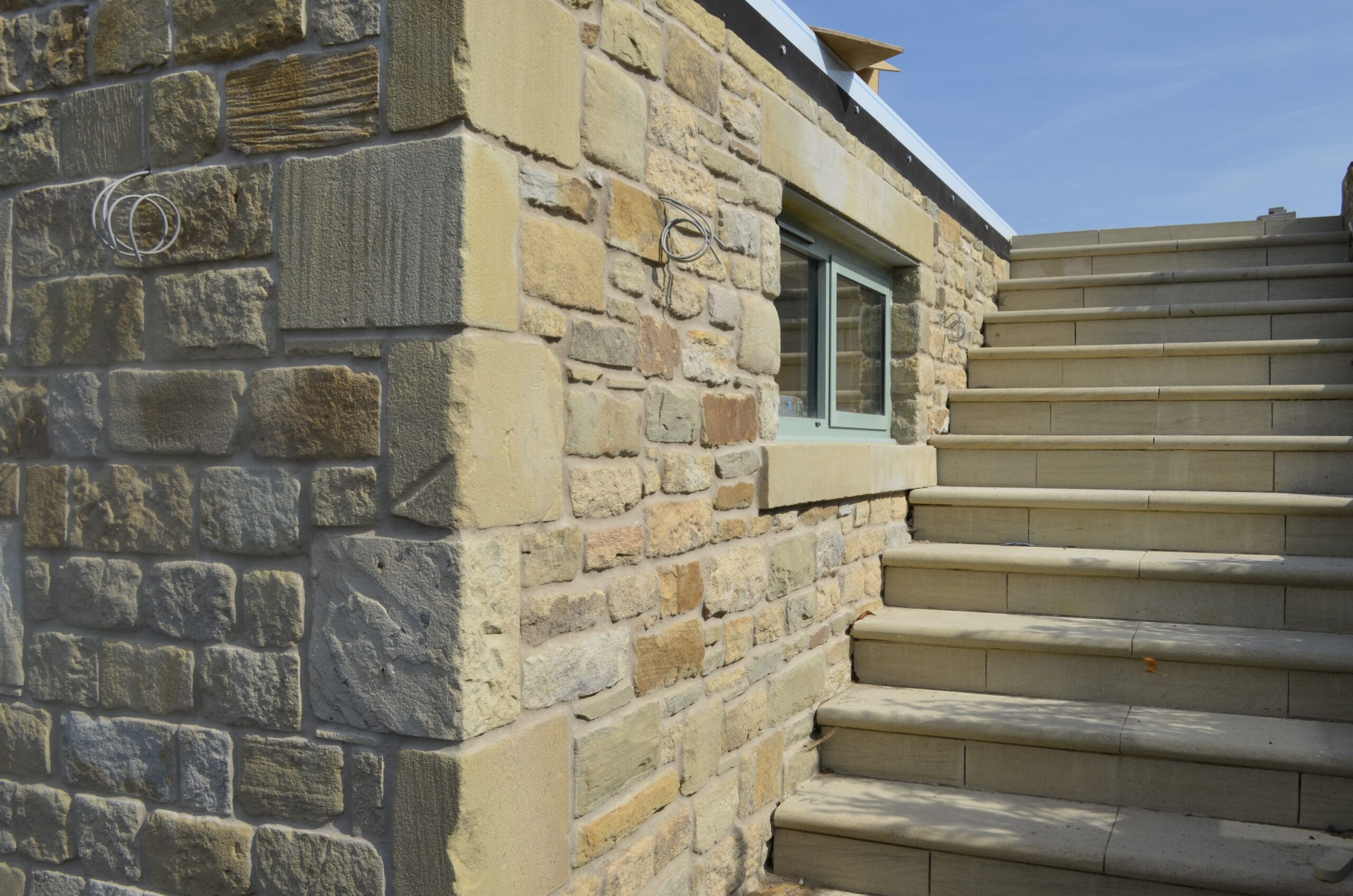 Close-up of hand tooled quoins integrated into a natural stone wall, showcasing the detailed craftsmanship and precise stone alignment.